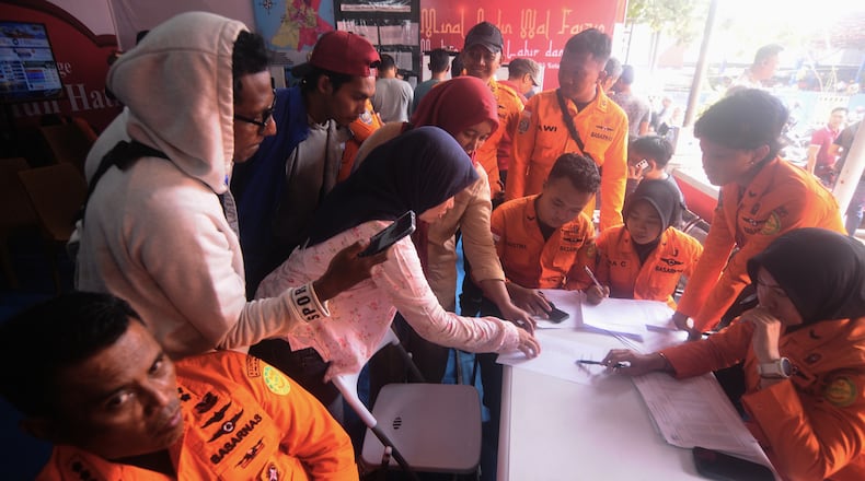 People look for the names of their family members on a passenger list after a ferry overturned in bad weather in the Java Sea, at the rescuers command center in Banjarmasin, South Kalimantan, Indonesia, Sunday, Sept. 13, 2026. (AP Photo/Iman Satria)