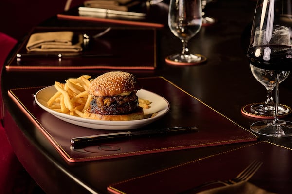 A burger sits on the bar at an upscale steakhouse with leather placemats