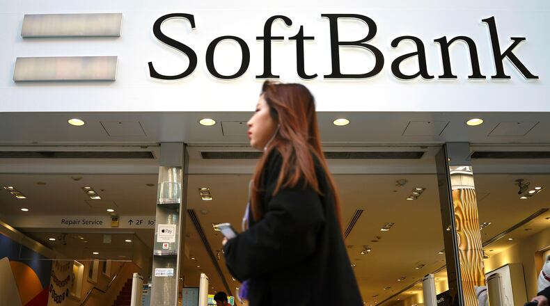 FILE - A woman walks in front of SoftBank store in Ginza shopping district in Tokyo, Jan. 20, 2020. (AP Photo/Eugene Hoshiko, File)