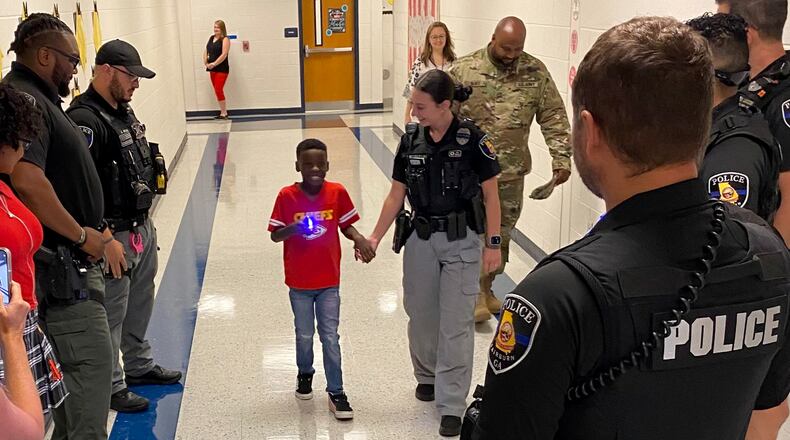 Officers escort Jonathan Astree to his first day of first grade. The boy's father, a Fairburn police officer, was recently killed in a crash.