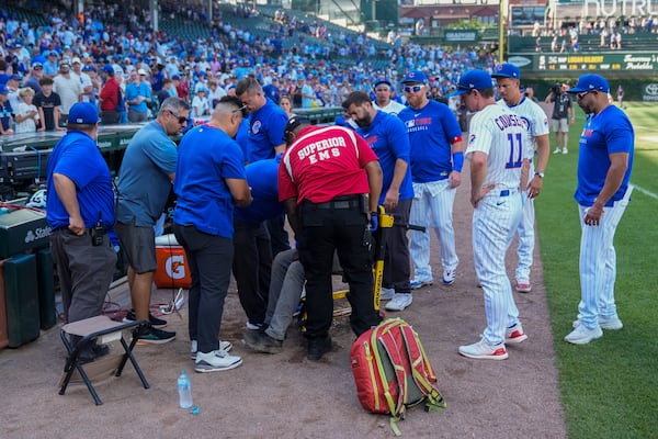 Members of the Chicago Cubs and others stand around as emergency services personnel tend to a Wrigley Field staff member after a hot and humid baseball game against the Seattle Mariners, Saturday, June 21, 2025, in Chicago. (AP Photo/Erin Hooley)