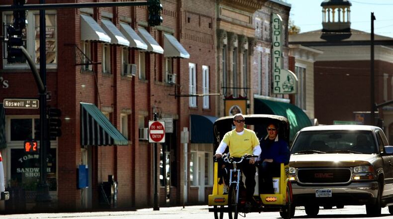 Brian Buckalew, owner of Marietta Pedicabs, gives a ride to customers in historic Marietta Square on a November morning in 2010. Woodstock is moving to adopt a pedicab ordinance adapted from Marietta’s. AJC FILE / Jason Getz / jgetz@ajc.com