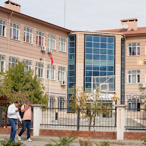 People walk past a vocational and technical high school in the Turgutlu district of Manisa province, western Turkey, Tuesday, Sept. 22, 2026, after a gunman opened fire near the school. (IHA via AP)