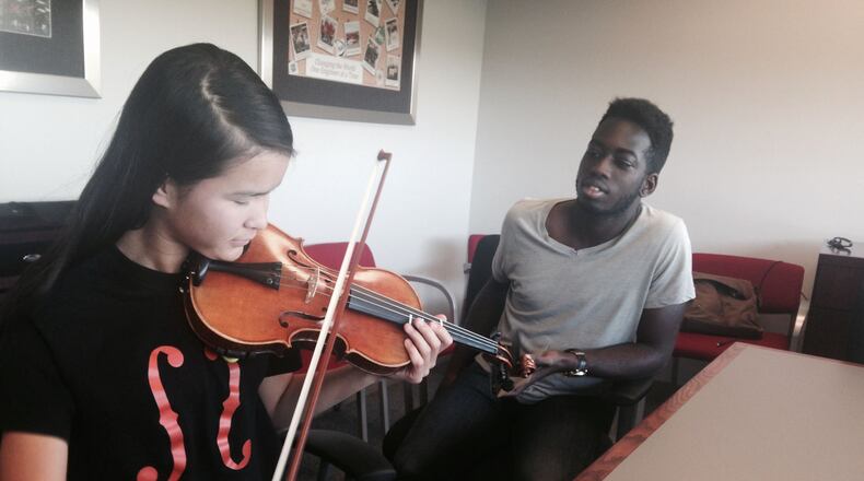 Sarah Valentiner of DeKalb plays her violin using the prosthetic designed by Northern Illinois University engineering student, Oleseun Taiwo, of Naperville. (Denise Crosby/Chicago Tribune/TNS)