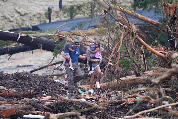 People climb over debris on a bridge atop the Guadalupe River after a flash flood swept through the area Saturday, July 5, 2025, in Ingram, Texas. (AP Photo/Julio Cortez)