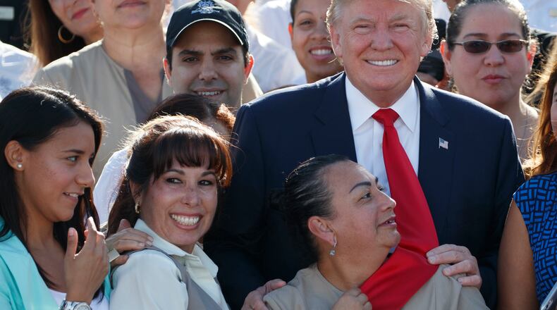 An employee of Republican presidential candidate Donald Trump grabs his tie as they pose for photographs during an event at Trump National Doral on Tuesday in Miami. AP/ Evan Vucci