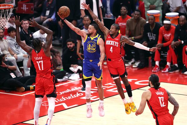 Golden State Warriors' Stephen Curry (30) scores against Houston Rockets' Tari Eason (17) and Jalen Green (4) during the first half of Game 1 of an NBA basketball first-round playoff series in Houston, Sunday, April 20, 2025. (Scott Strazzante/San Francisco Chronicle via AP)