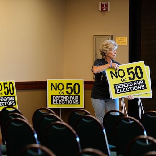 Brenda Haynes places signs throughout a conference room before a No on Prop 50 rally in Redding, Calif., Tuesday, Oct. 21, 2025. (AP Photo/Godofredo A. Vásquez)