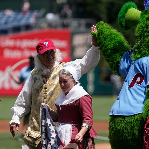 Bill Robling as Benjamin Franklin, left, and Carol Spacht as Betsy Ross, center, greet the Philadelphia Phillies mascot, the Phillie Phanatic before a baseball game between the Phillies and the Pittsburgh Pirates Thursday, July 2, 2026, in Philadelphia. (AP Photo/Matt Slocum)