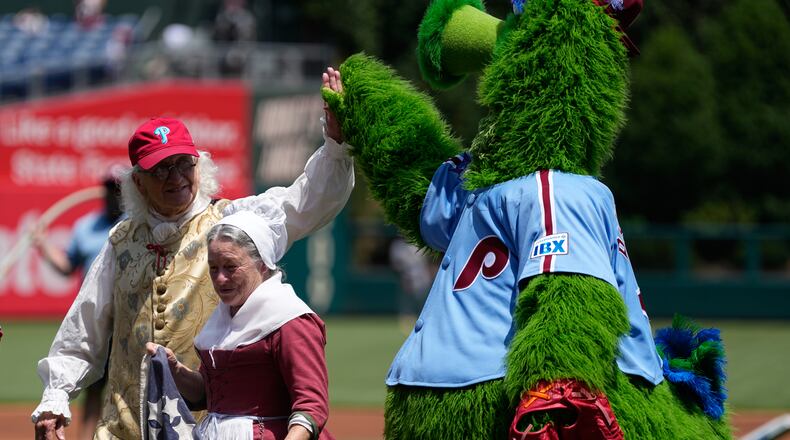 Bill Robling as Benjamin Franklin, left, and Carol Spacht as Betsy Ross, center, greet the Philadelphia Phillies mascot, the Phillie Phanatic before a baseball game between the Phillies and the Pittsburgh Pirates Thursday, July 2, 2026, in Philadelphia. (AP Photo/Matt Slocum)