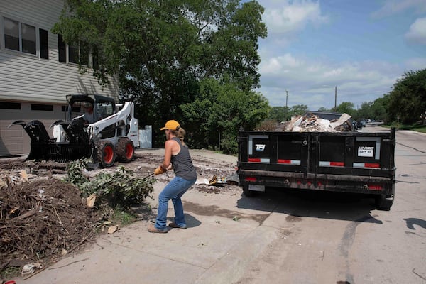 A volunteer removes tree debris from a flood-damaged home on Guadalupe Street in Kerrville, Texas, on July 12, 2025. (AP Photo/Gabriela Aoun Angueira)