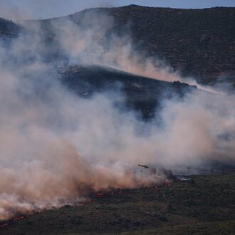 A firefighting helicopter drops water on the flames as a wildfire advances near Burgohondo, Ávila province, Spain, Friday, July 24, 2026. (AP Photo/Manu Fernandez)