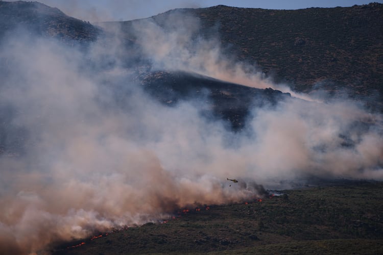 A firefighting helicopter drops water on the flames as a wildfire advances near Burgohondo, Ávila province, Spain, Friday, July 24, 2026. (AP Photo/Manu Fernandez)