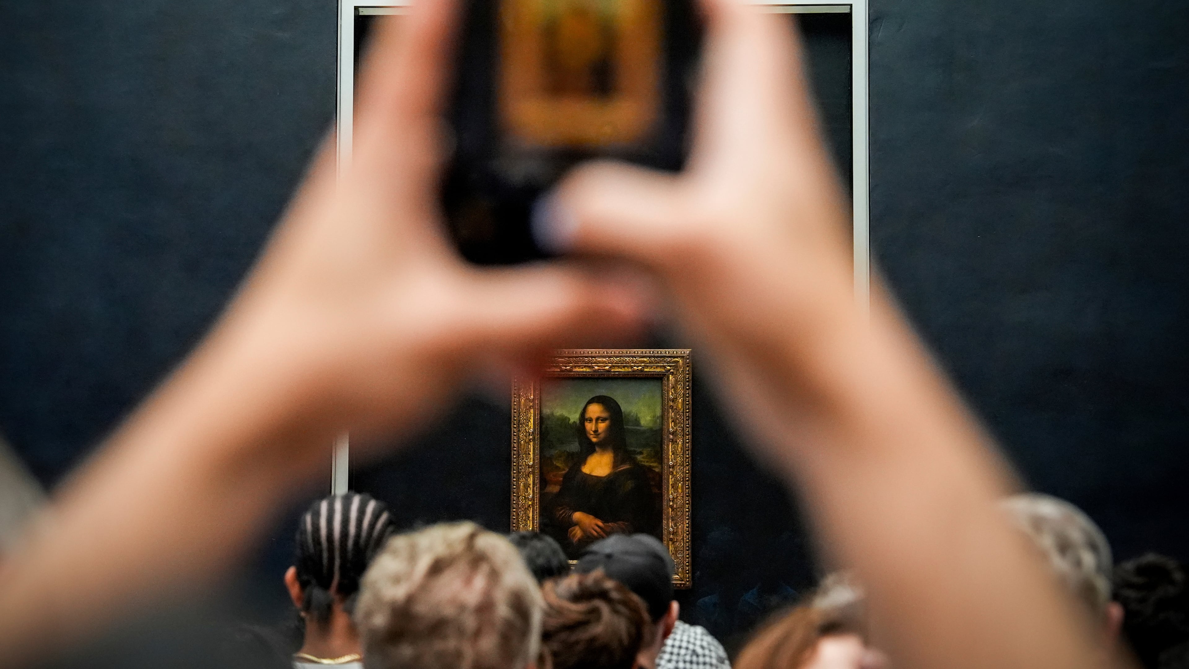 FILE - A person photographs Leonardo da Vinci's painting Mona Lisa at the Louvre museum, Aug. 31, 2025, in Paris. (AP Photo/Julia Demaree Nikhinson, file)