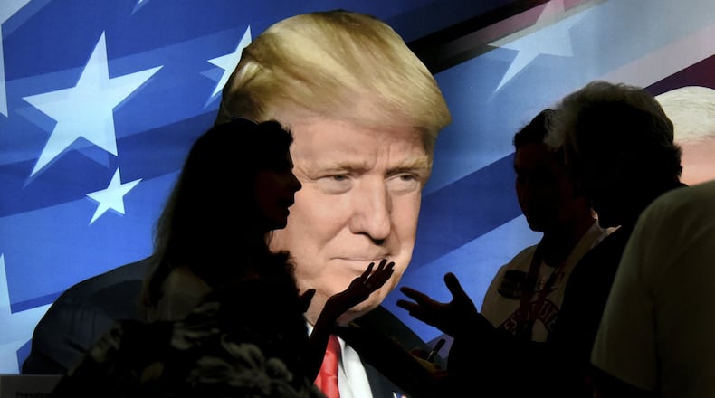 Republicans stop to talk in front of a backlit image of President Trump during the opening day of the Georgia State GOP convention Friday, June 2, 2017 in Augusta, Ga. (Michael Holahan/The Augusta Chronicle via AP)