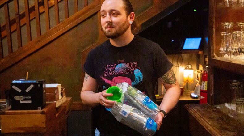 Brickhouse Pub bartender Trevor Cannon restocks the new to-go cups in Decatur Friday, December 10, 2021. STEVE SCHAEFER FOR THE ATLANTA JOURNAL-CONSTITUTION