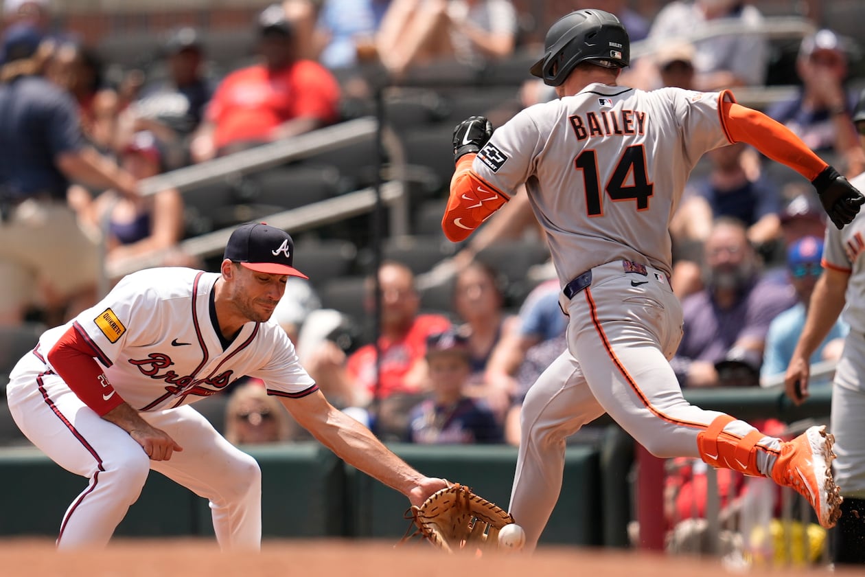 San Francisco Giants' Patrick Bailey (14) beats the tag by Atlanta Braves first baseman Matt Olson (28) in the seventh inning of a baseball game, Wednesday, July 23, 2025, in Atlanta. (AP Photo/Mike Stewart)