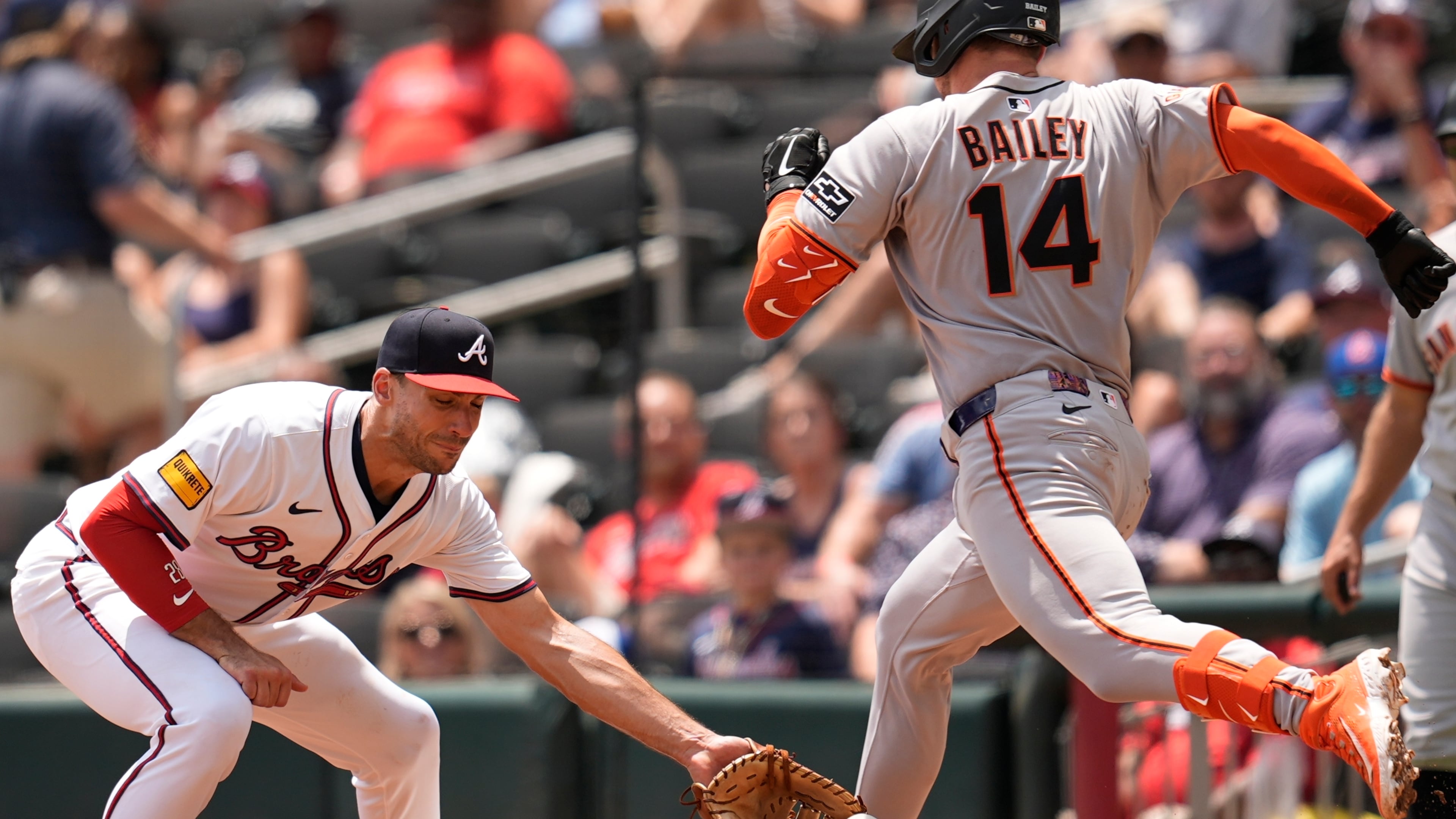 San Francisco Giants' Patrick Bailey (14) beats the tag by Atlanta Braves first baseman Matt Olson (28) in the seventh inning of a baseball game, Wednesday, July 23, 2025, in Atlanta. (AP Photo/Mike Stewart)