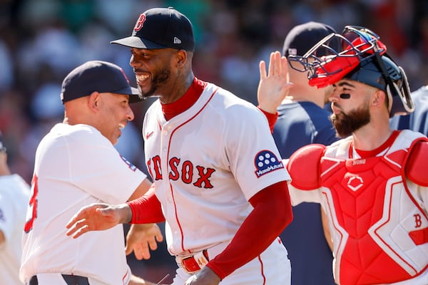 Boston Red Sox's Alex Cora, left, celebrates with relief pitcher Aroldis Chapman, center, after their team defeated the Tampa Bay Rays in a baseball game, Sunday, July 13, 2025, in Boston. (AP Photo/Greg M. Cooper)