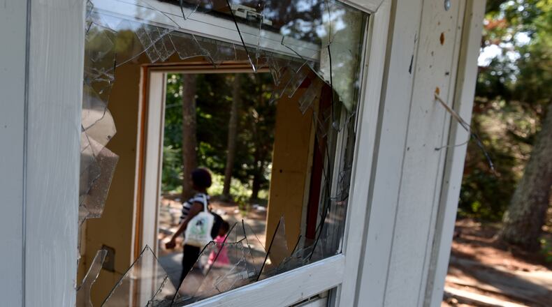 September 7, 2016 Decatur, GA: A woman and small cild walk past the shattered window of the guard shack at Creekside Forest Apartment Homes in Decatur. The complex has fallen into disrepair. The few residents who remain are living rent free but with no maintenance services or support. The leasing office has been closed for several months, mail is no longer delivered, windows are broken, and litter covers the ground. BRANT SANDERLIN/BSANDERLIN@AJC.COM