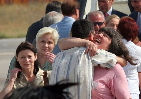 FILE - Bulgarian nurses Valentina Manolova Siropulo, left, Nasya Stoitcheva Nenova, second left, look on as Valia Georgieva Chervenisahka, right, hugs an unidentified man in front of the French presidential air plane after their arrival in the Bulgarian capital Sofia, July 24, 2007. (AP Photo, File)