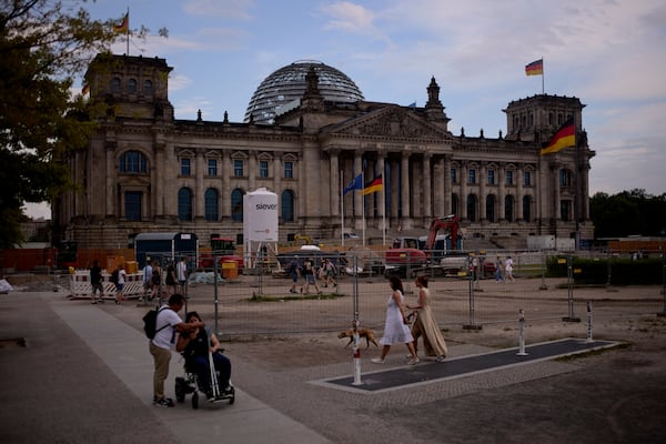 People walk in front of the Reichtag Building, in Berlin, Germany, Friday, May 2, 2025. (AP Photo/Markus Schreiber)
