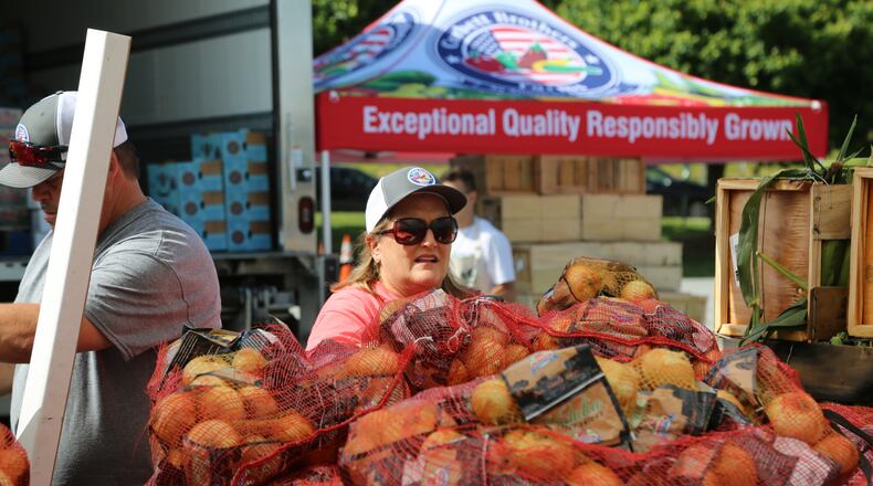 Carla Harwell of Corbett Brothers of Lake Park, Ga., watches for the next customer to arrive over bags of Vidalia onions during the Georgia Grown market in Cobb County in May. The state Department of Agriculture helped set up truck markets for Georgia vegetable farmers who were facing a loss of sales because of shut-downs caused by the spread of COVID-19 during the spring of 2020.