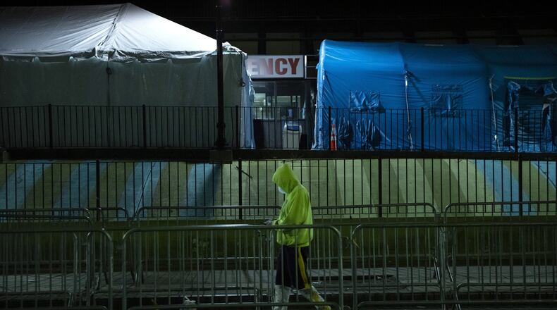 A man walks by the triage tents outside of Elmhurst Hospital in New York on March 26, 2020. (AP Photo/Marshall Ritzel)