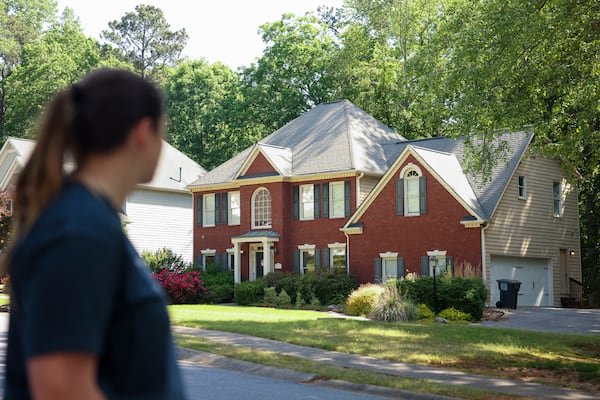 Neighbor Jillian Scelsi looks at the Powder Springs home where a man illegally squatted before being arrested last week. (Jason Getz / AJC)

