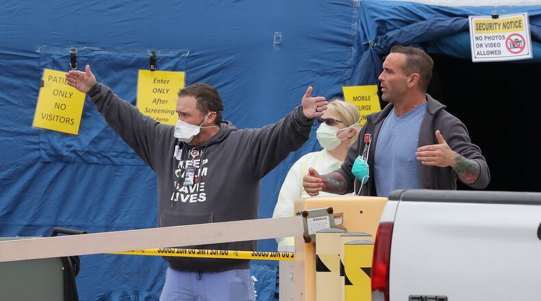 Medical workers give instructions at the entrance to the mobile surge unit tent outside the emergency entrance at WellStar Kennestone Hospital. Curtis Compton ccompton@ajc.com