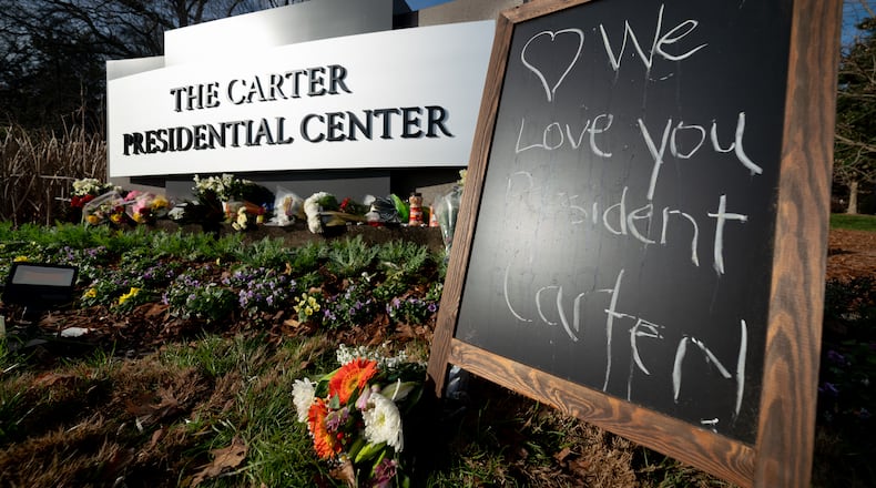 A chalkboard that reads "We love you President Carter!" sits outside the Carter Presidential Center in Atlanta.