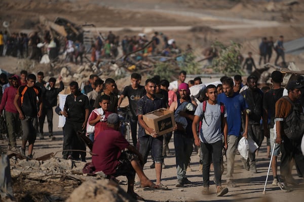 Palestinians carry humanitarian aid packages near the Gaza Humanitarian Foundation distribution center operated by the U.S.-backed organization in Khan Younis, southern Gaza Strip, Thursday, June 26, 2025. (AP Photo/Abdel Kareem Hana)