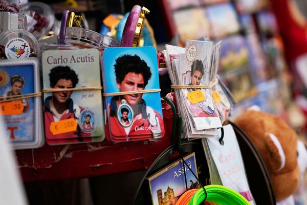 Pictures of 15-year-old Carlo Acutis, an Italian boy who died in 2006 of leukemia, are displayed for sale at a kiosk in Assisi, Italy, on Saturday, March 1, 2025. (AP Photo/Gregorio Borgia)