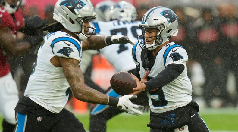 Carolina Panthers quarterback Bryce Young, right, hands off to running back Rico Dowdle (5) during the first half of an NFL football game Saturday, Jan. 3, 2026, in Tampa, Fla. (AP Photo/Chris O'Meara)