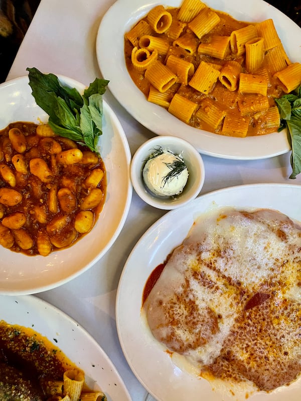 A top-down view of several pasta dishes on a white tablecloth.