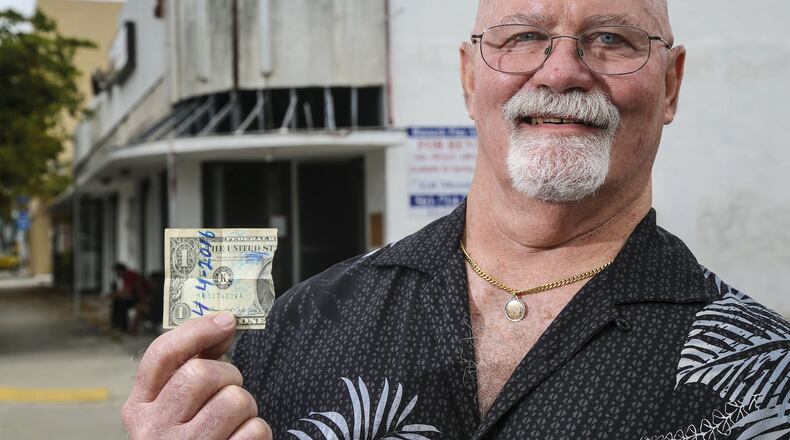 Steve Morris stands outside the old El Cid bar with half of a dollar bill that 40 years ago he and Joe Whitehead wrote “4/4/2016” on, ripped in half and kept. The two friends vowed to meet and have a drink at the Cid 40 years in the future. (Lannis Waters / The Palm Beach Post)