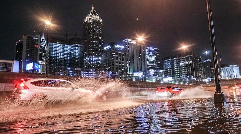 Motorists plow through standing water along Techwood Drive near 16th Street on Monday, March 27, 2023, during early morning thunderstorms in Atlanta. (John Spink / John.Spink@ajc.com)