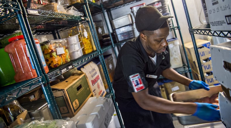 Marcus Bell finds a spot to rest a pan as he grabs fresh chicken breasts inside the walk-in cooler at Fresh to Order at Hartsfield-Jackson International. Tight space is another challenge restaurants face at the world’s busiest airport. JONATHAN PHILLIPS / SPECIAL