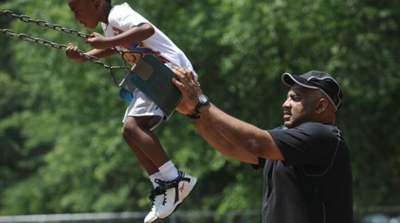 Frederick Judkins makes sure his son, Frederick Judkins Jr., gets a good arc on the swing. (File photo)