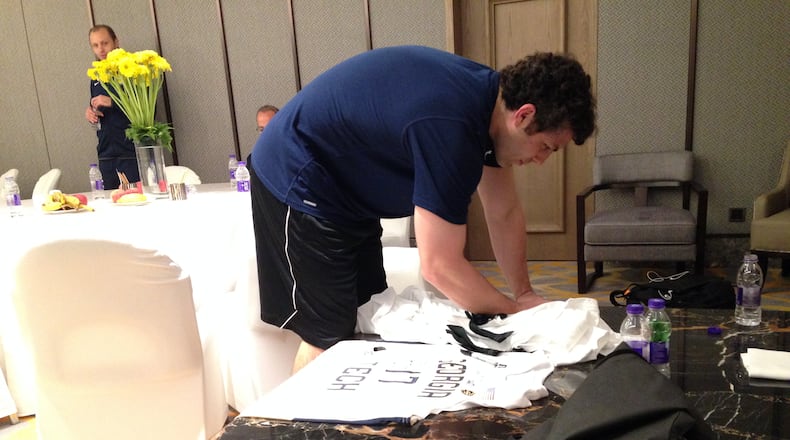Georgia Tech coach Josh Pastner autographs a jersey to be presented as a gift during the team's stay in China. The Yellow Jackets will play UCLA Saturday (Friday night in the U.S.) in Shanghai. (AJC photo by Ken Sugiura)