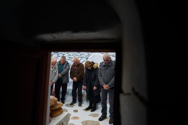 The faithful stand outside the chapel of Panagia Evangelistria, in Amorgos island, Greece, as Orthodox Christian monk Father Spyridon of Amorgos conducts the Divine Liturgy, on Tuesday, March 25, 2025. (AP Photo/Petros Giannakouris)