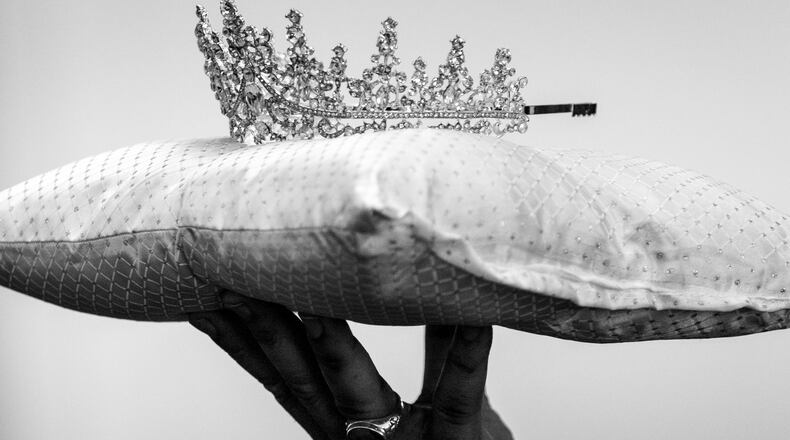 A funeral attendant carries a crown for Beverly Brown, 69, at Willie Watkins Funeral Home chapel in Atlanta on Saturday, Dec. 30, 2023. (Arvin Temkar/AJC)