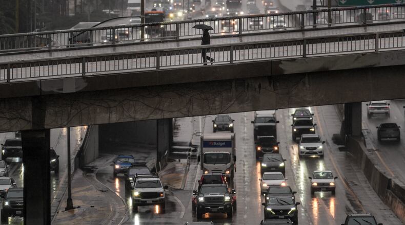 A pedestrian with an umbrella walks on a bridge over the rain-soaked 110 Freeway in Los Angeles Friday, Nov. 14, 2025. (AP Photo/Jae C. Hong)
