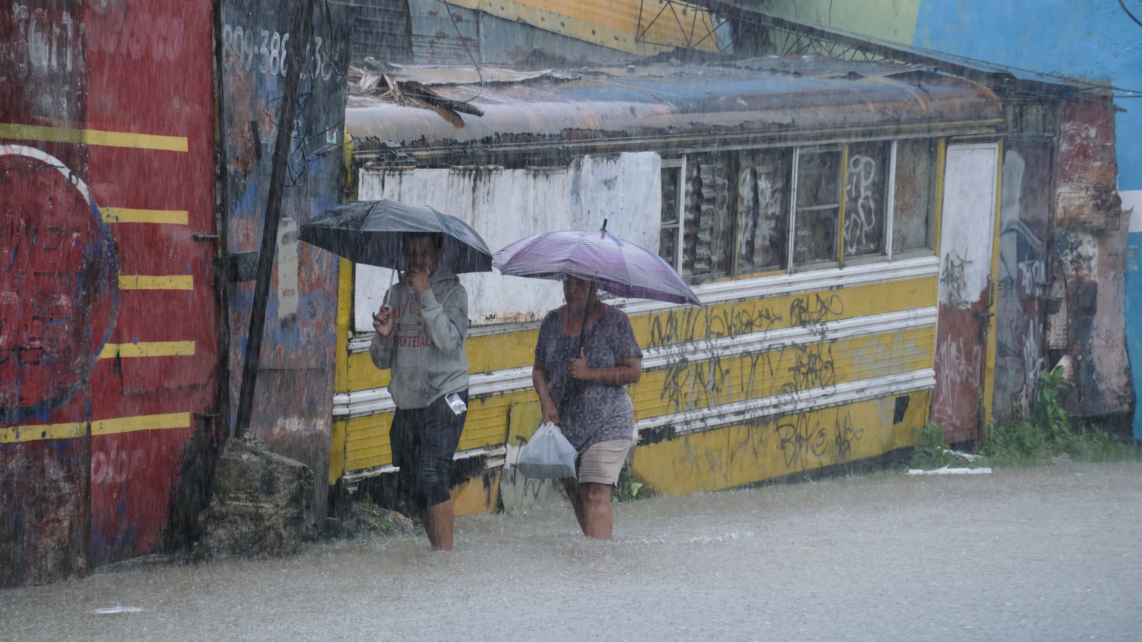 People wade through a street flooded by rains caused by Tropical Storm Melissa in Santo Domingo, Dominican Republic, Friday, Oct. 24, 2025. (AP Photo/Ricardo Hernandez)