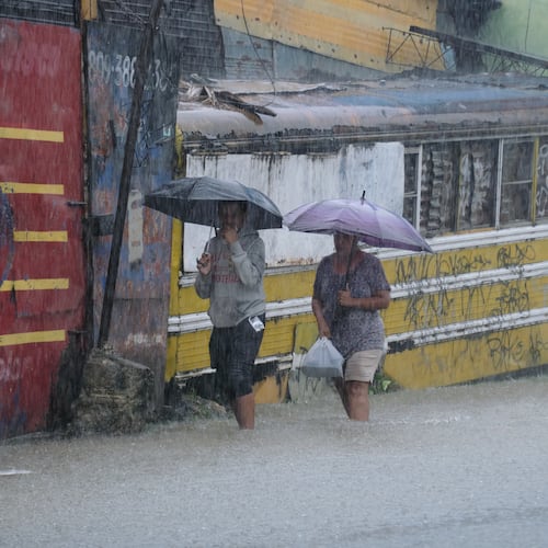 People wade through a street flooded by rains caused by Tropical Storm Melissa in Santo Domingo, Dominican Republic, Friday, Oct. 24, 2025. (AP Photo/Ricardo Hernandez)