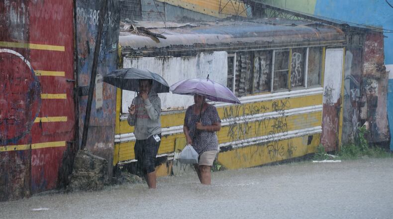 People wade through a street flooded by rains caused by Tropical Storm Melissa in Santo Domingo, Dominican Republic, Friday, Oct. 24, 2025. (AP Photo/Ricardo Hernandez)