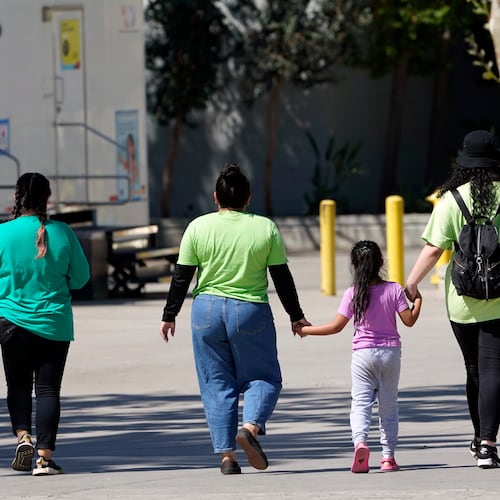 FILE - A child holds hands with workers at an emergency shelter for migrant children, July 2, 2021, in Pomona, Calif. (AP Photo/Marcio Jose Sanchez, Pool, File)