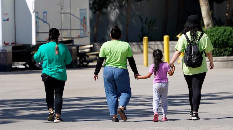 FILE - A child holds hands with workers at an emergency shelter for migrant children, July 2, 2021, in Pomona, Calif. (AP Photo/Marcio Jose Sanchez, Pool, File)