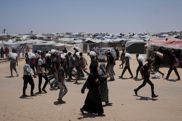 Palestinians carry bags containing food and humanitarian aid packages delivered by the Gaza Humanitarian Foundation, a U.S.-backed organization, in Rafah, southern Gaza Strip, Sunday, June 8, 2025. (AP Photo/Abdel Kareem Hana)