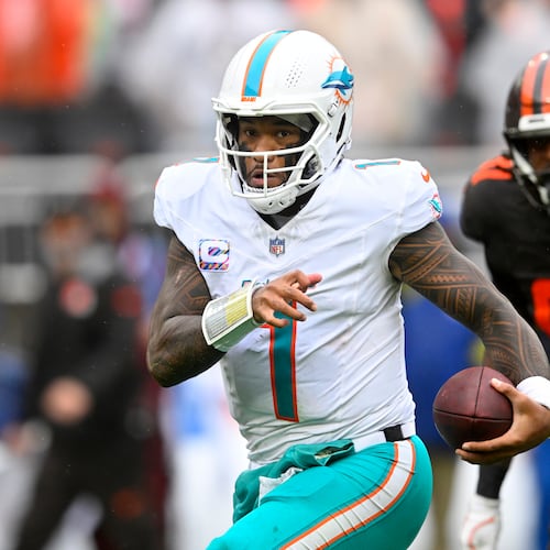 Miami Dolphins quarterback Tua Tagovailoa (1) scrambles from Cleveland Browns defensive end Alex Wright (91) in the first half of an NFL football game in Cleveland, Sunday, Oct. 19, 2025. (AP Photo/David Richard)